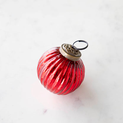 Mini red ribbed ornament on a marble table.