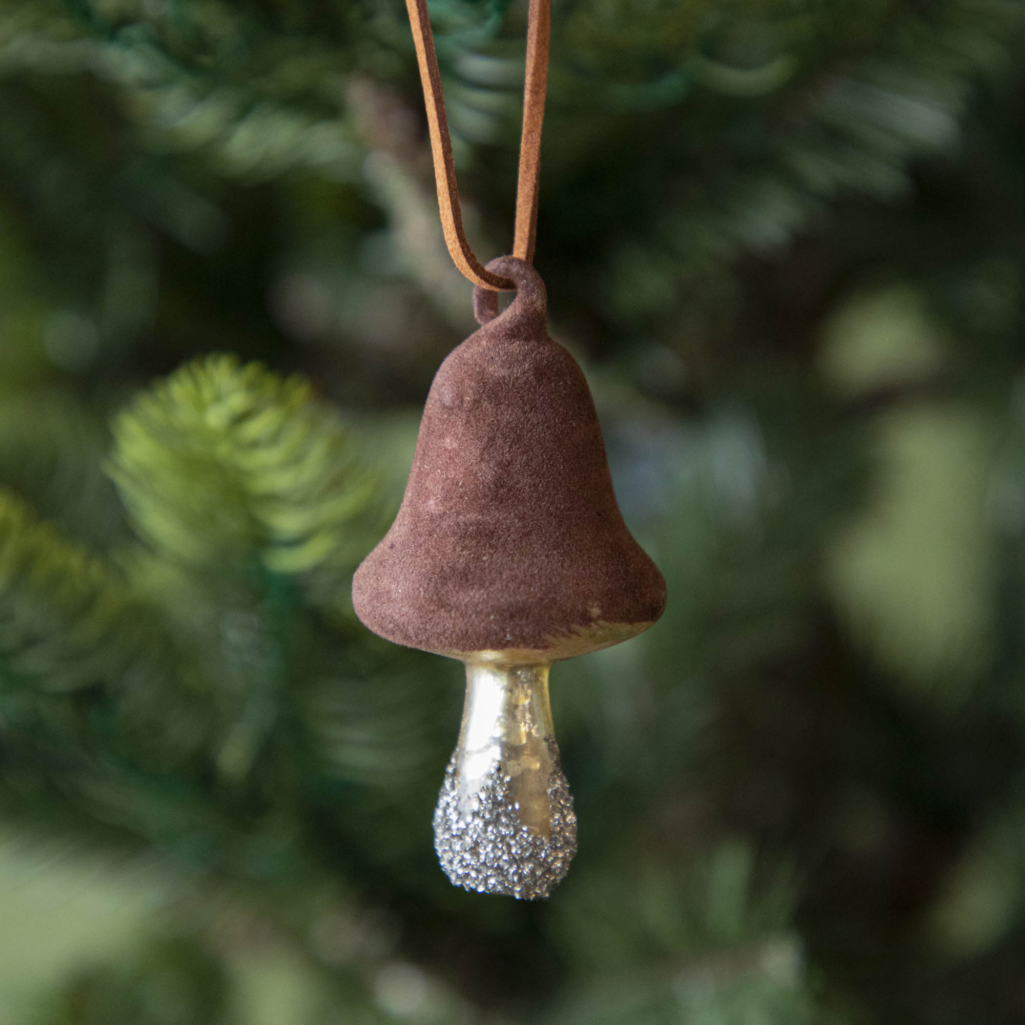 A Glass Mushroom with Velvet Top Ornament hanging on a tree.