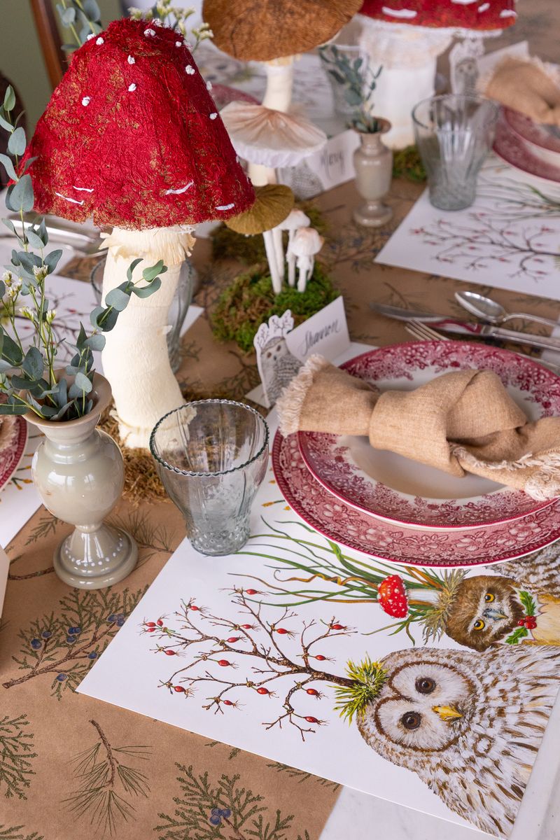 Decorative table setting with red mushroom-shaped lamps, plates, and owl-themed placemats.
