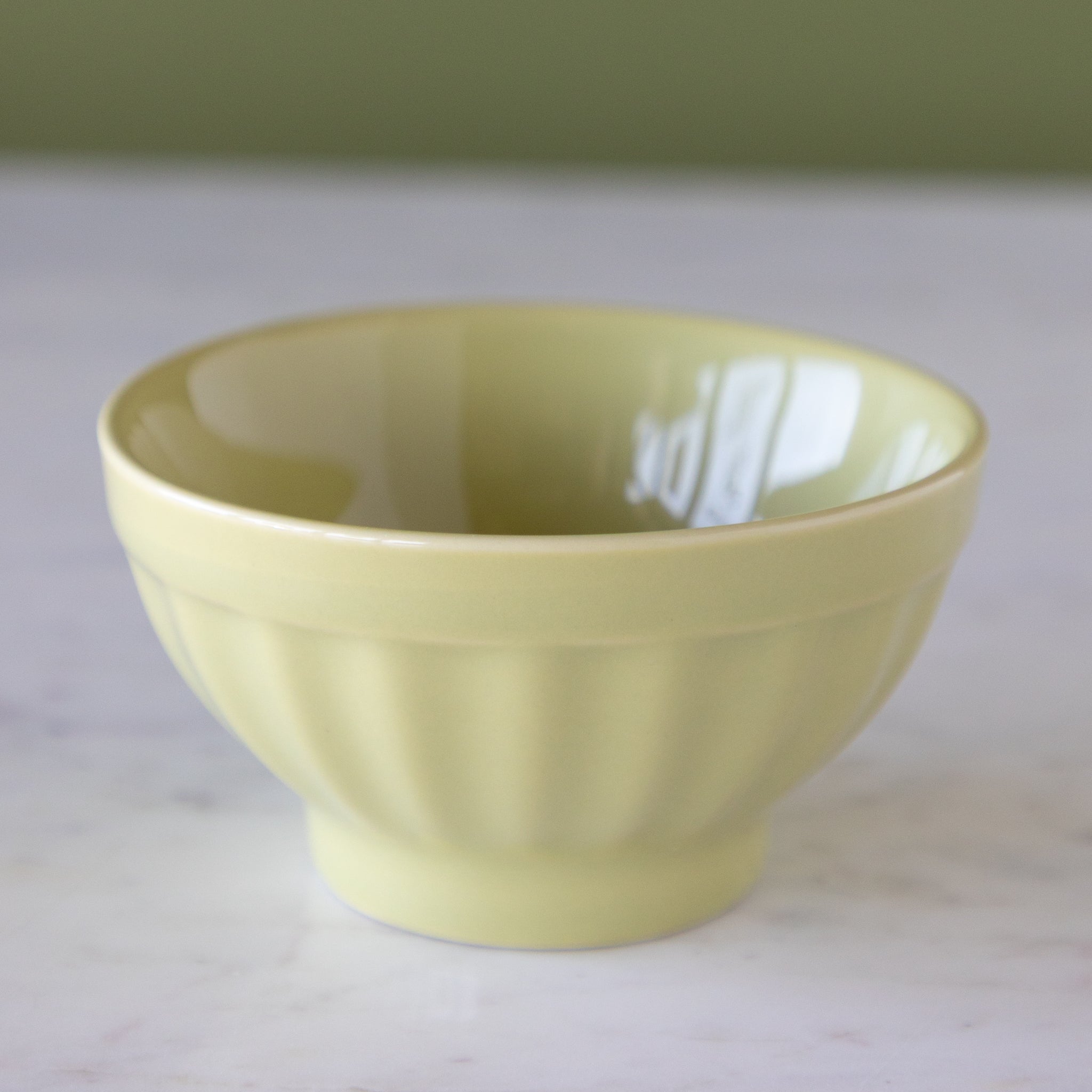 Pistachio-colored ceramic ice cream bowl on a marble table.