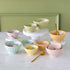 Set of colorful ceramic Sorbet Bowls in two sizes filled with various sprinkles and gold spoons on a marble stable.