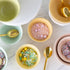 Colorful Sorbet Bowls with decorative sprinkles and gold spoons on a marble surface.
