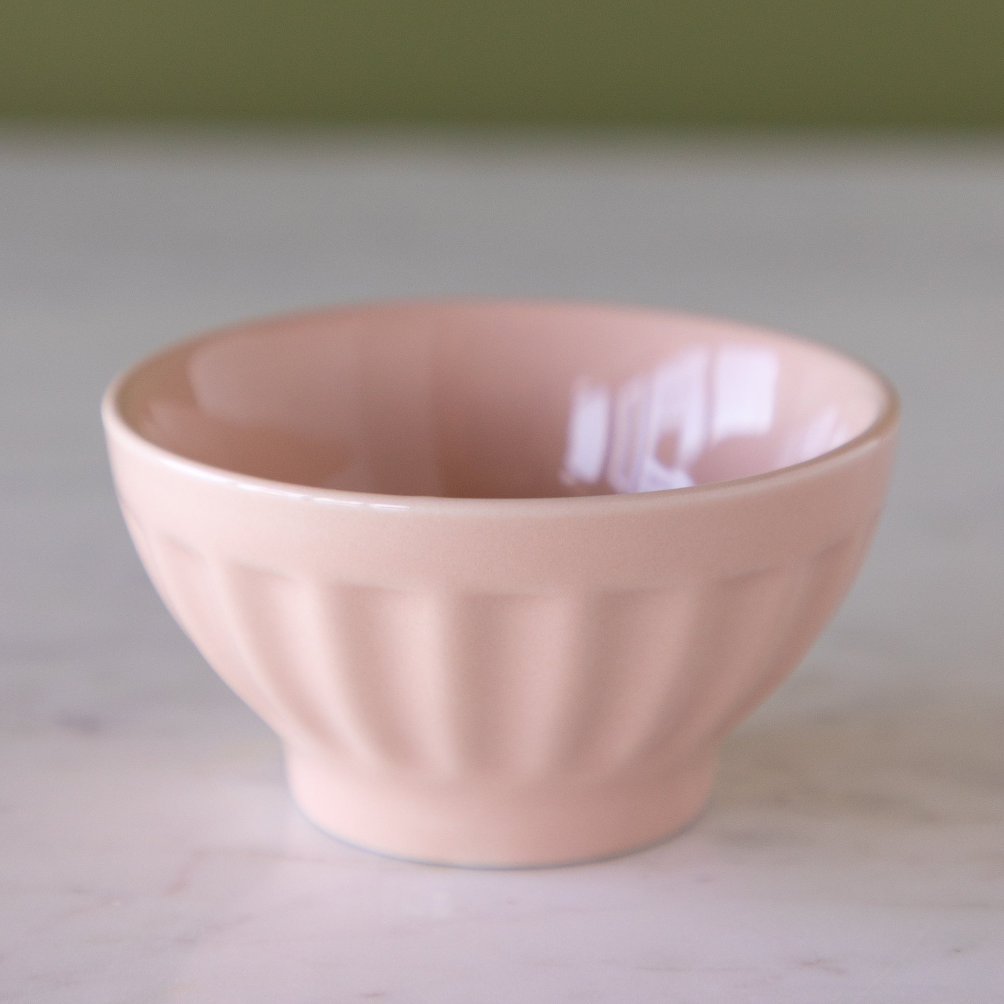 Blush pink colored ceramic pinch bowl on a marble table.