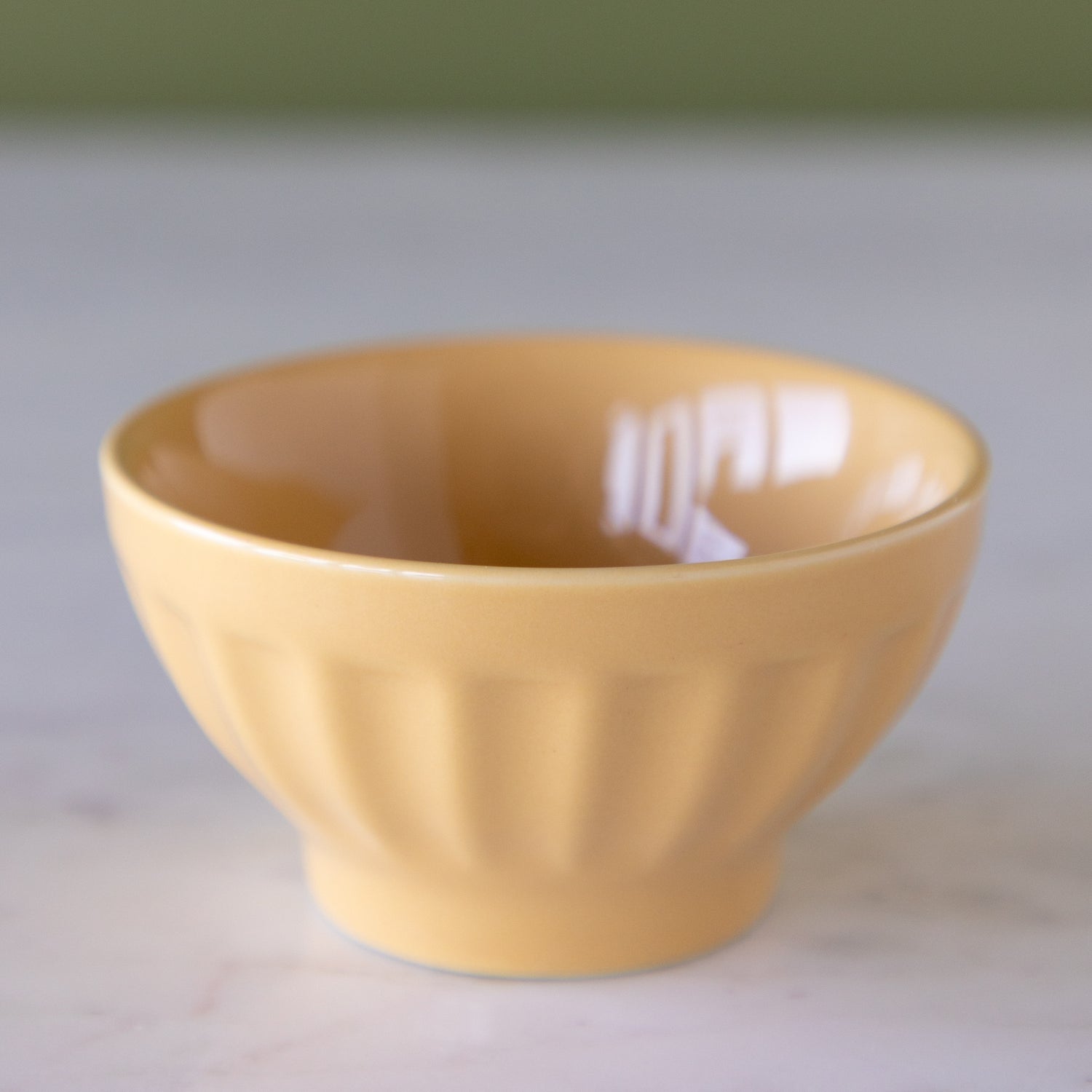 Toffee colored ceramic pinch bowl on a marble table.