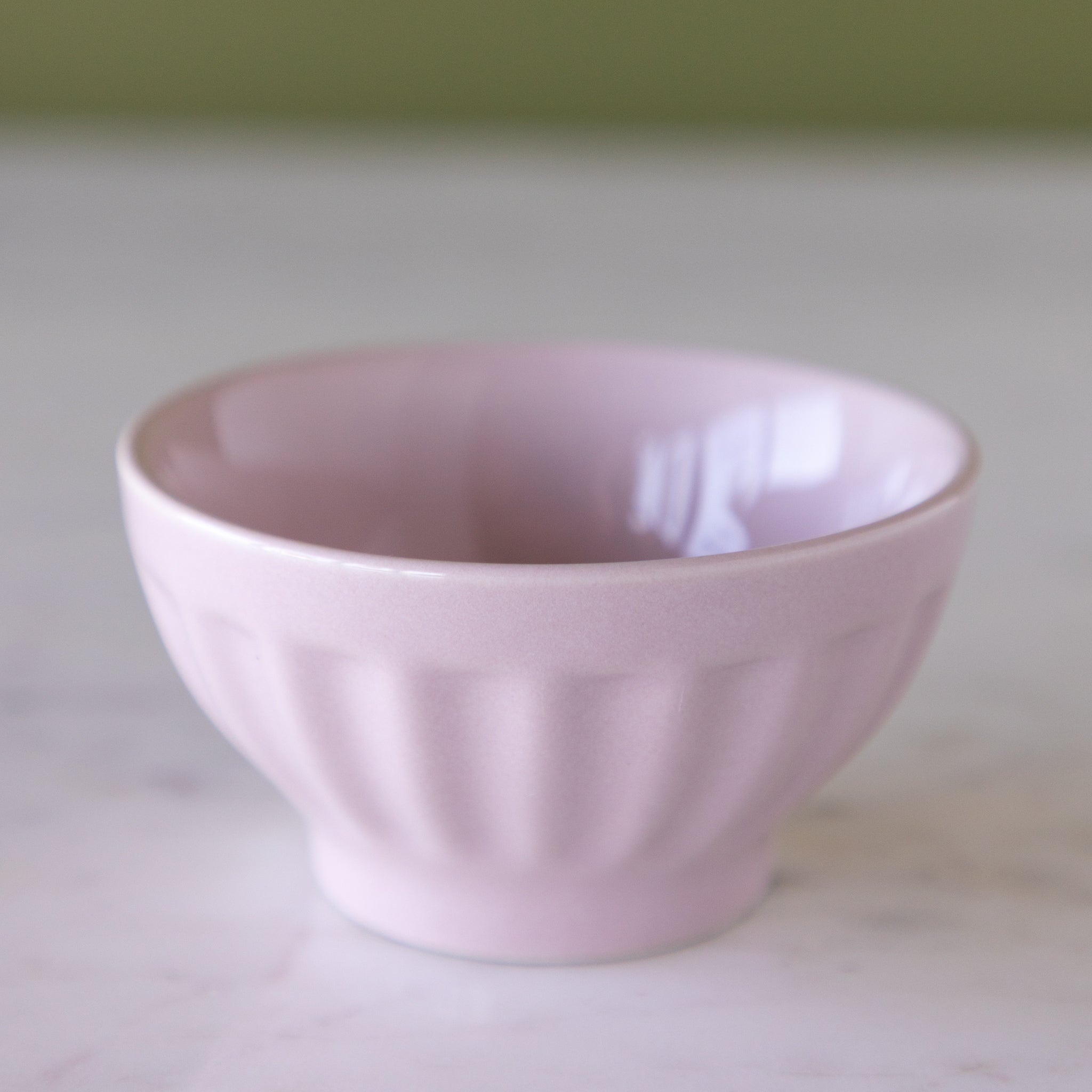Lavender ceramic pinch bowl on a marble table.