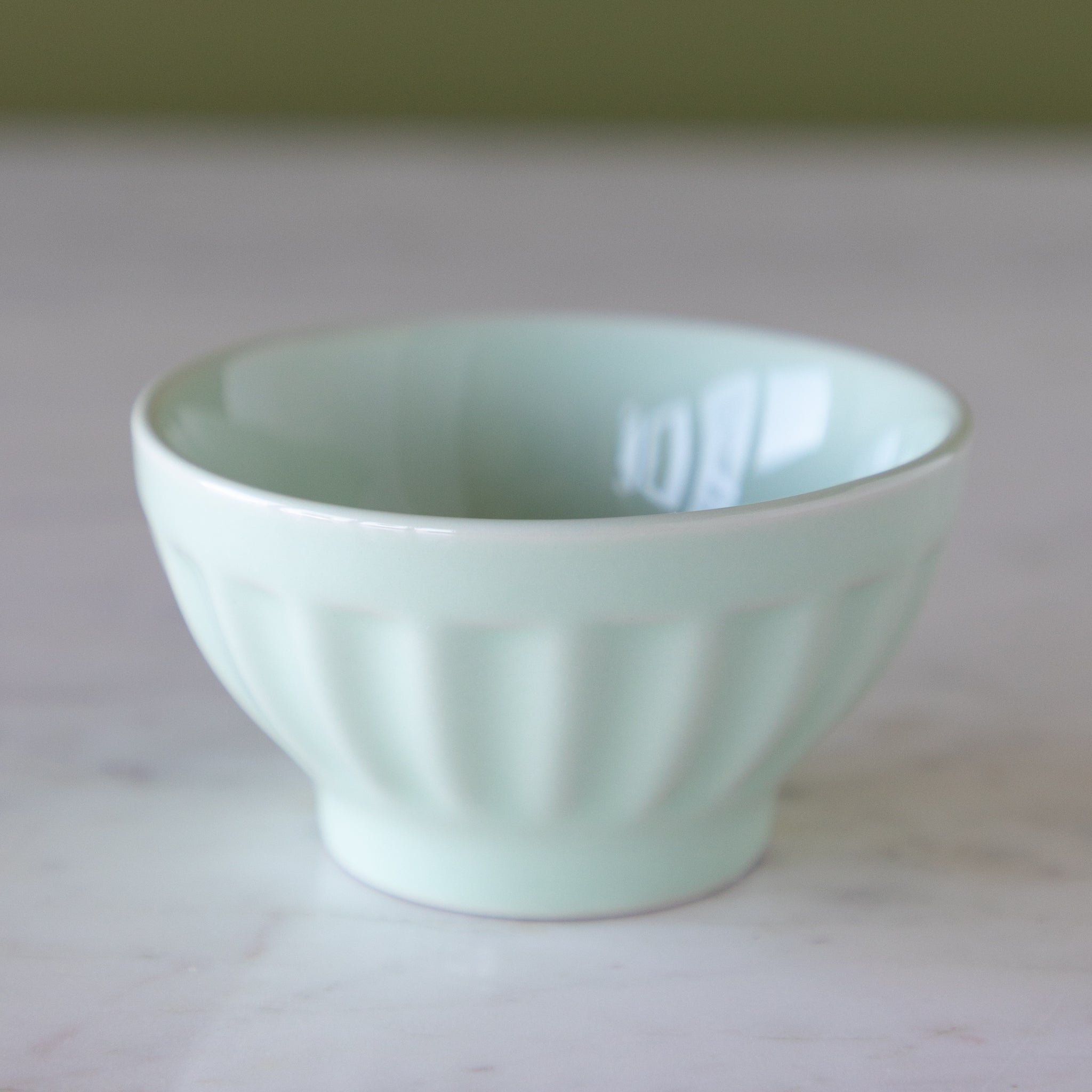 Light blue colored ceramic pinch bowl on a marble table.