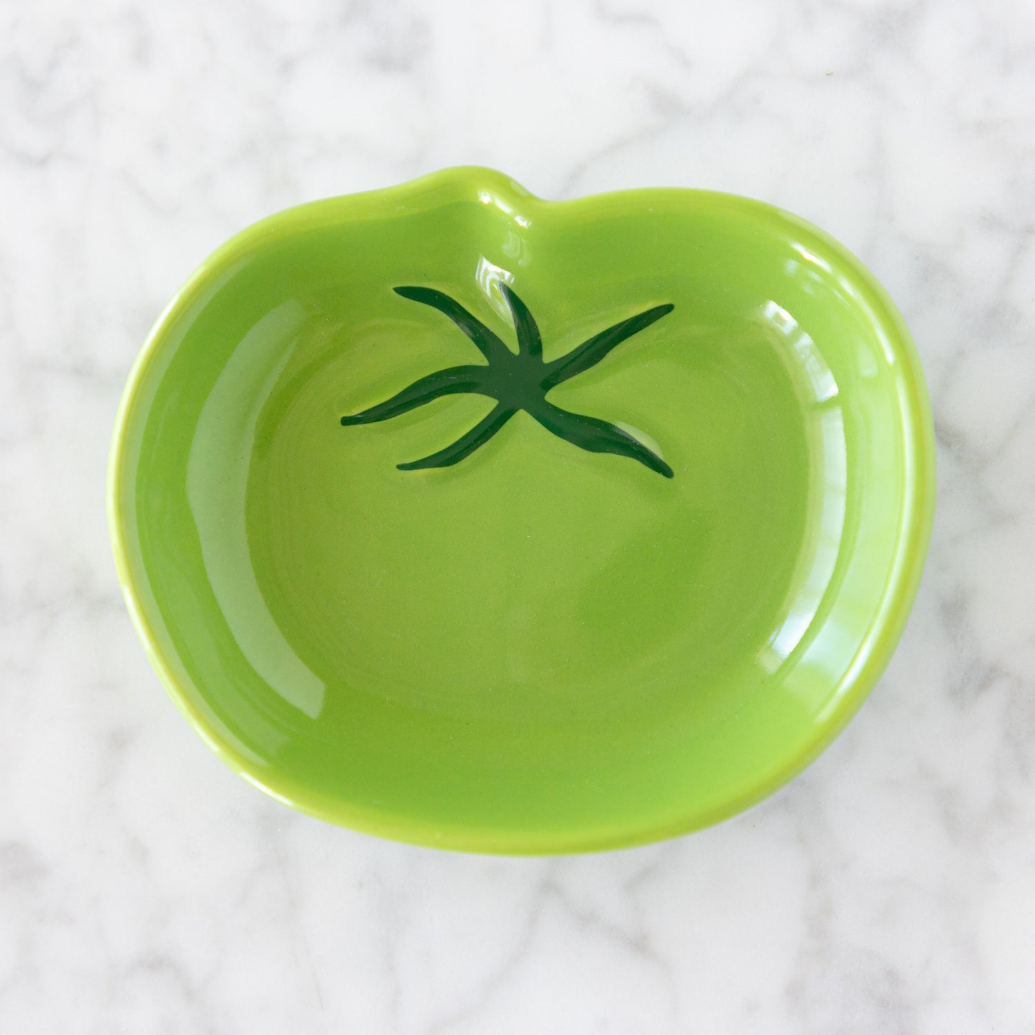 Green ceramic dish with a green stem design on a white textured background.