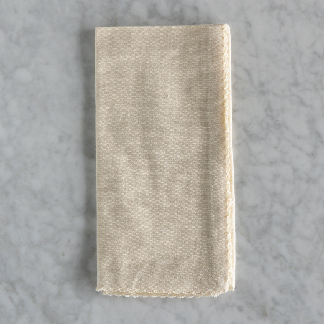 Folded beige napkin on a gray marble surface.