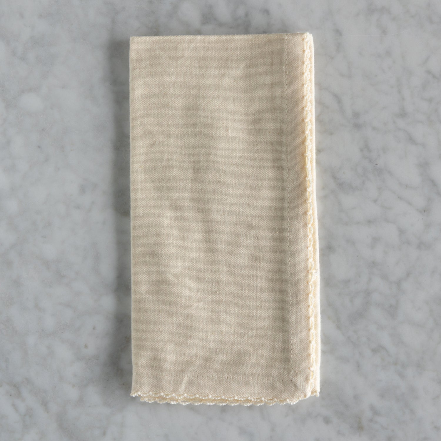 Folded beige napkin on a gray marble surface.