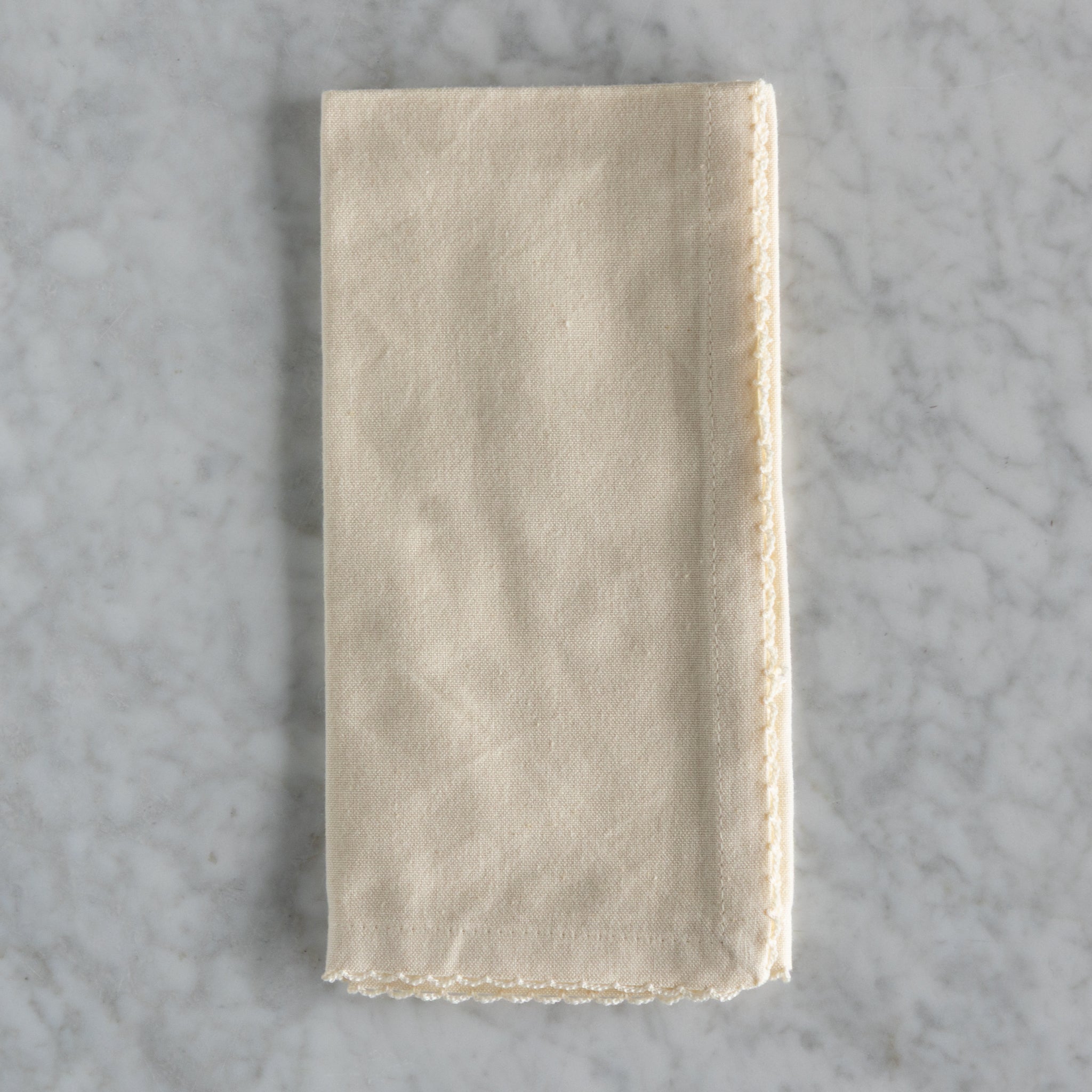 Folded beige napkin on a gray marble surface.