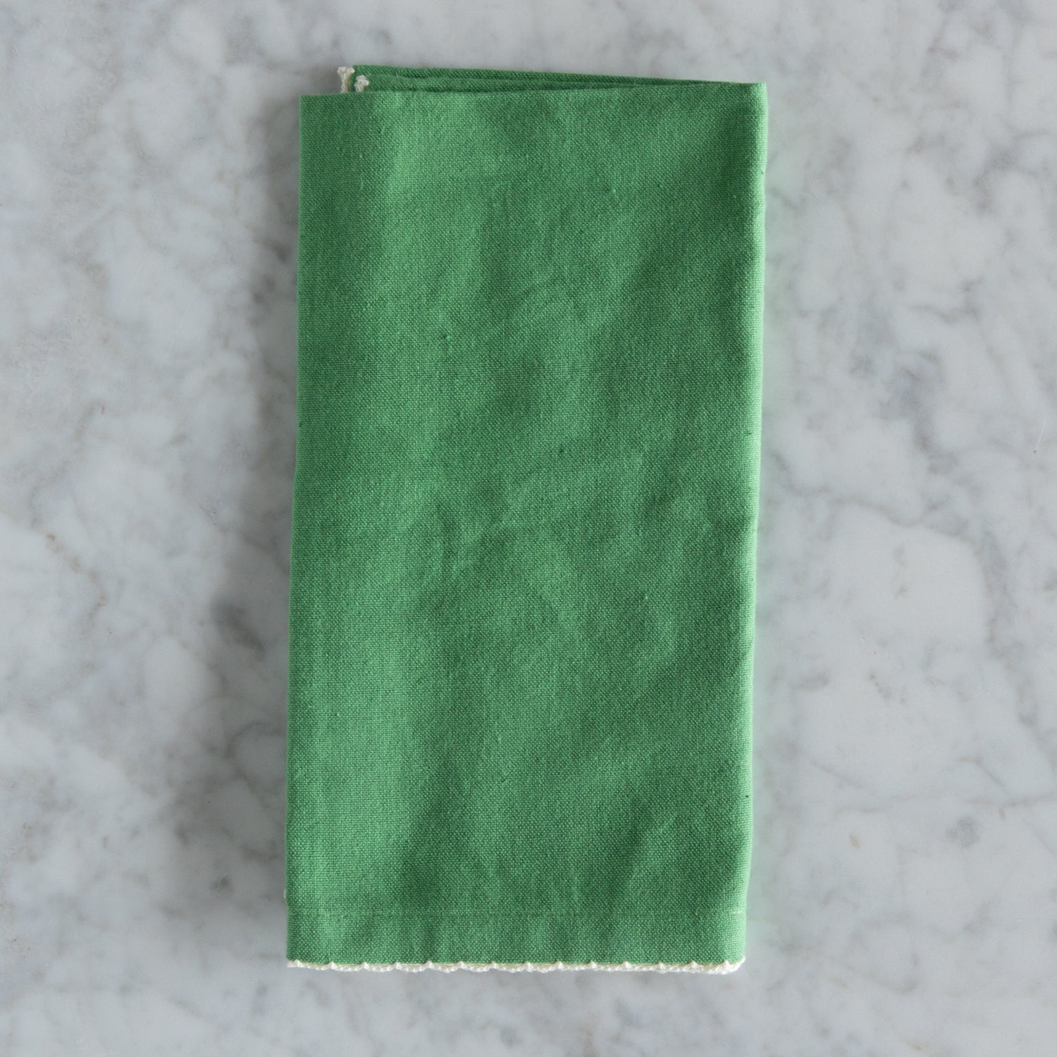 Green folded napkin on a gray marble surface.