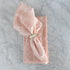 Pink lace napkin with a silver napkin ring on a marble surface.