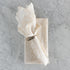 White lace napkin folded and tied with a silver napkin ring on a marble surface.