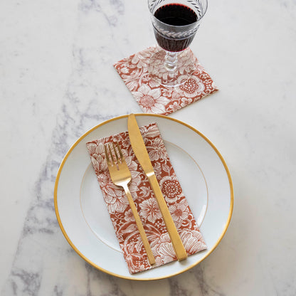 A simple, elegant place setting featuring a gold-rimmed plate with a Harvest Bouquet Guest Napkin on it, and a glass of wine with a Harvest Bouquet Cocktail Napkin under it.