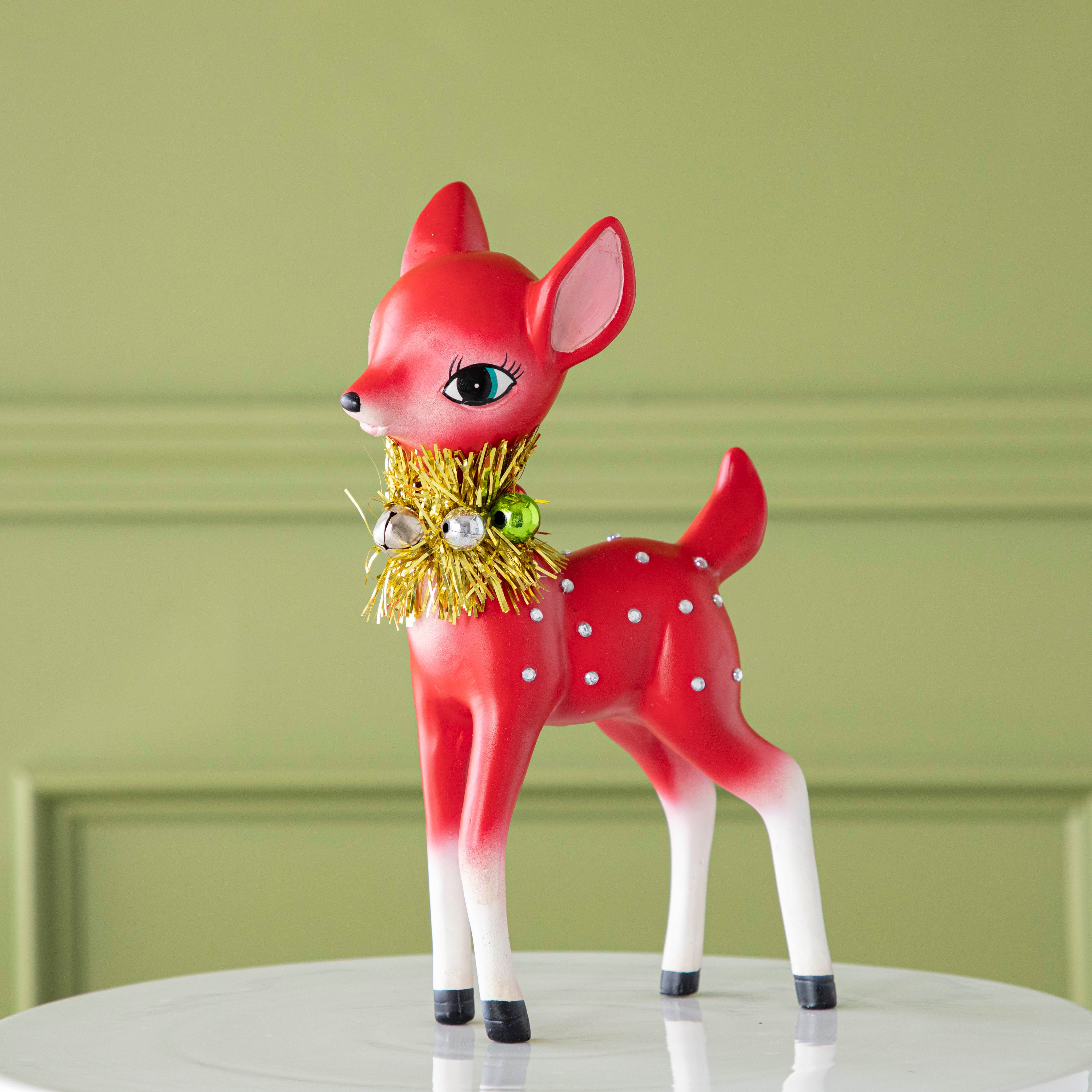 The red Retro Reindeer with a tinsel wreath with ornaments around its neck and jeweled body.