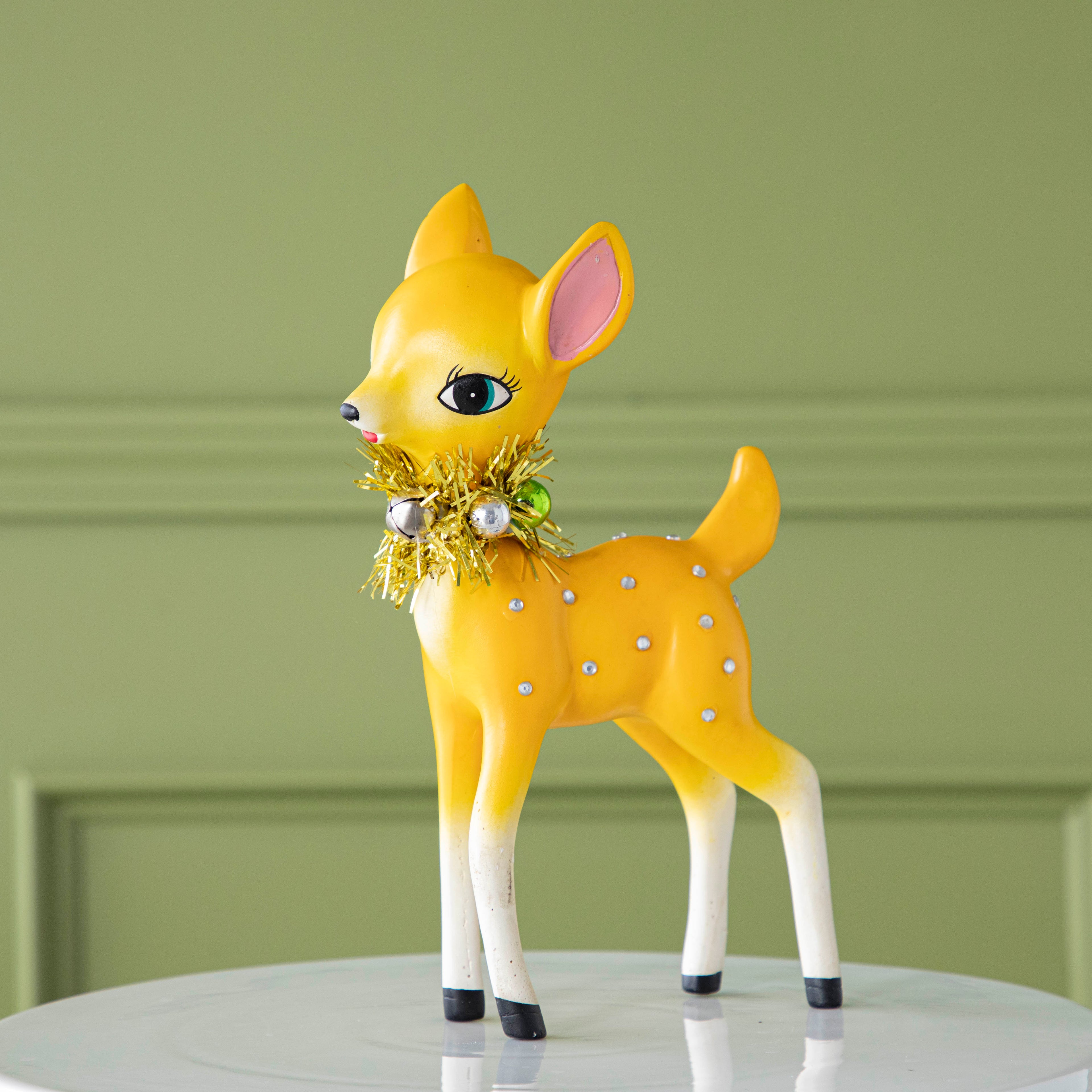 The yellow Retro Reindeer with a tinsel wreath with ornaments around its neck and jeweled body.