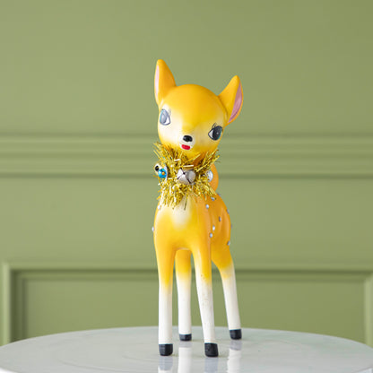 The yellow Retro Reindeer with a tinsel wreath with ornaments around its neck and jeweled body.