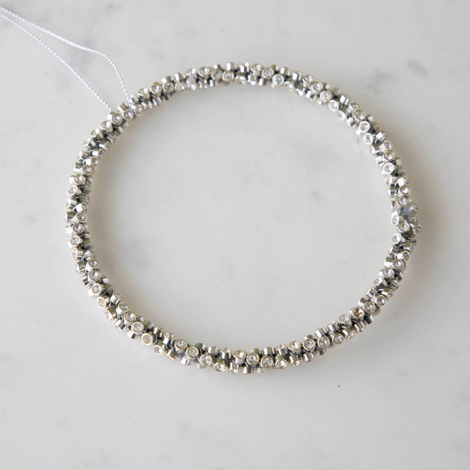 Silver Diamond Ring Ornament on a marble table.