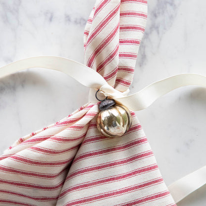 Embossed Antique Gold Mercury Glass Ornament tied to a red stripe napkin.
