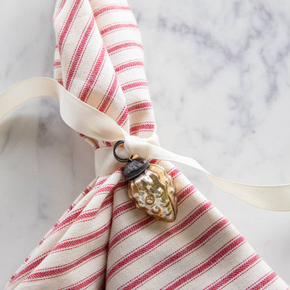 Embossed Antique Gold Mercury Glass Ornament tied to a red stripe napkin.