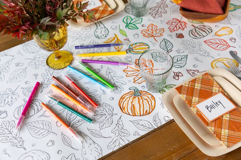 A fall tablescape featuring a partially colored in Autumn Coloring Runner, with colorful markers scattered on the table.