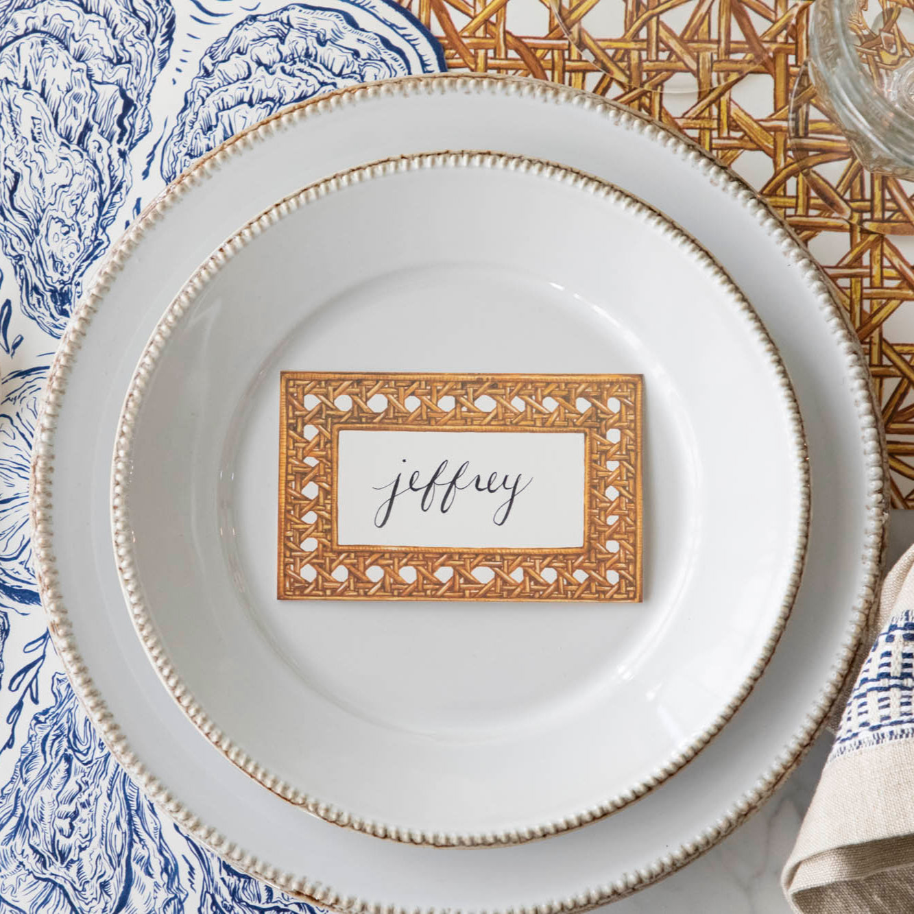 Rattan Weave Place Card with &quot;Jeffrey&quot; written on it, on a nautical themed table setting.