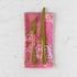 Gold fork and knife on a pink floral napkin against a white marble background.