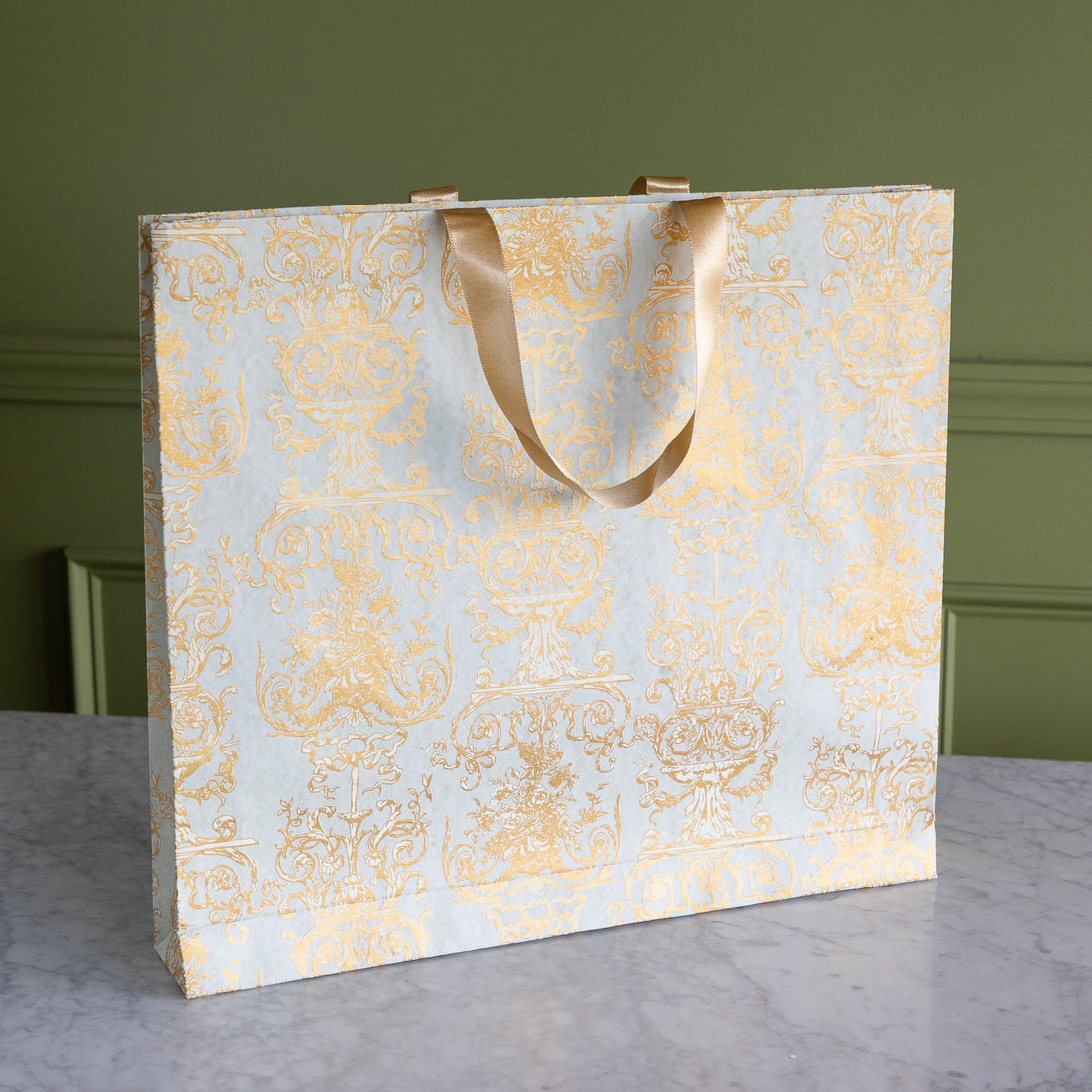 Decorative paper bag with gold patterns on a marble surface.
