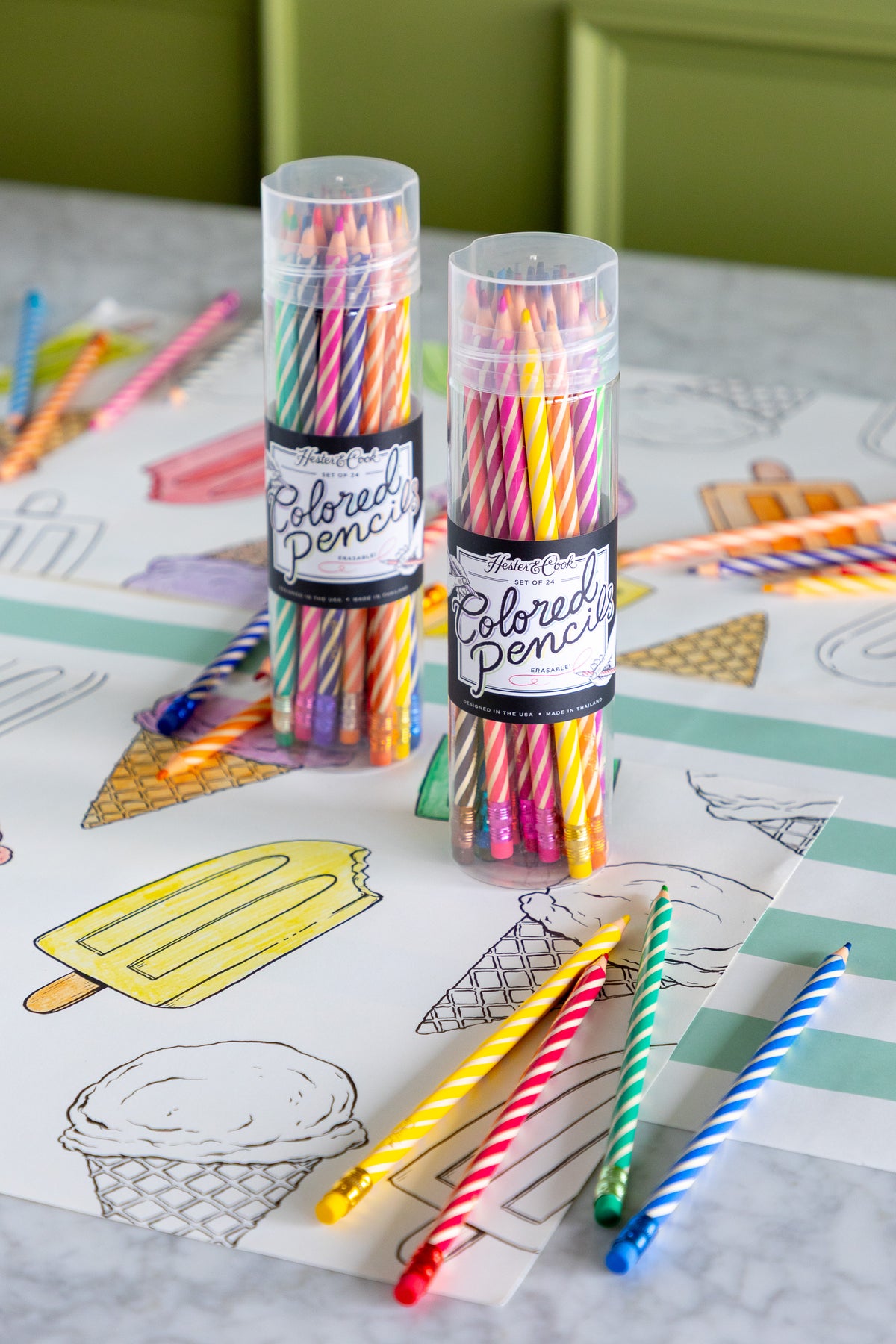 Two tubes of colored pencils on a coloring placemat with ice cream and popsicle illustrations.