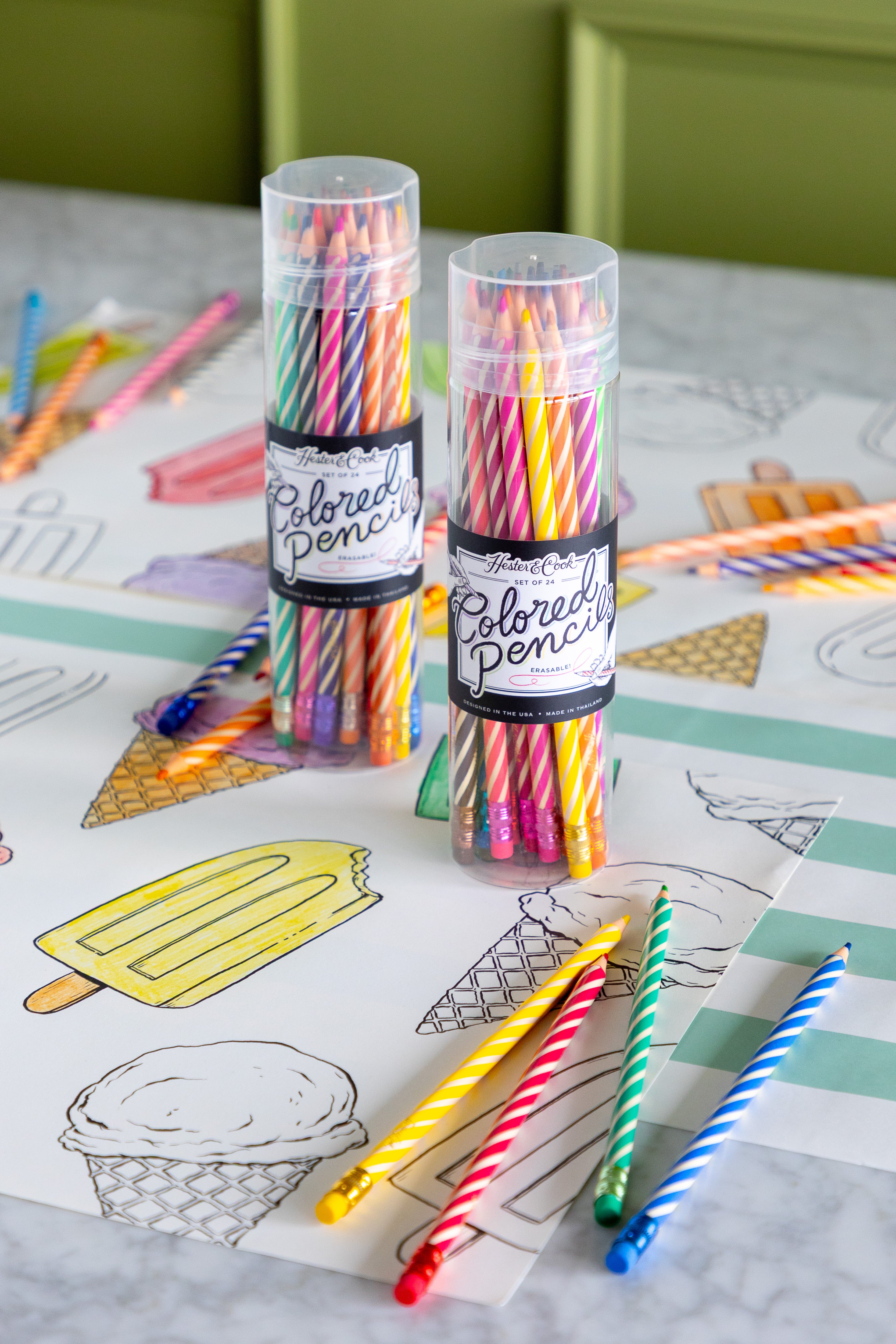 Two tubes of colored pencils on a coloring placemat with ice cream and popsicle illustrations.
