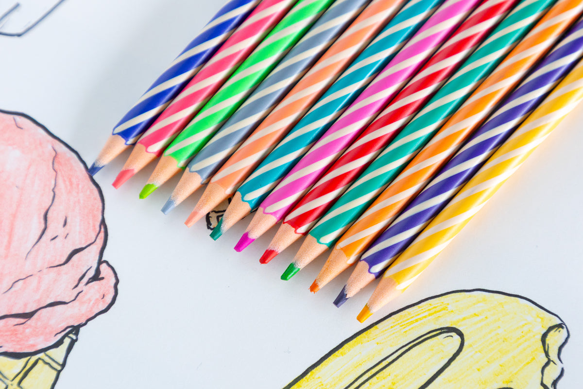 Colorful pencils on a white surface with a drawing of an ice cream cone.
