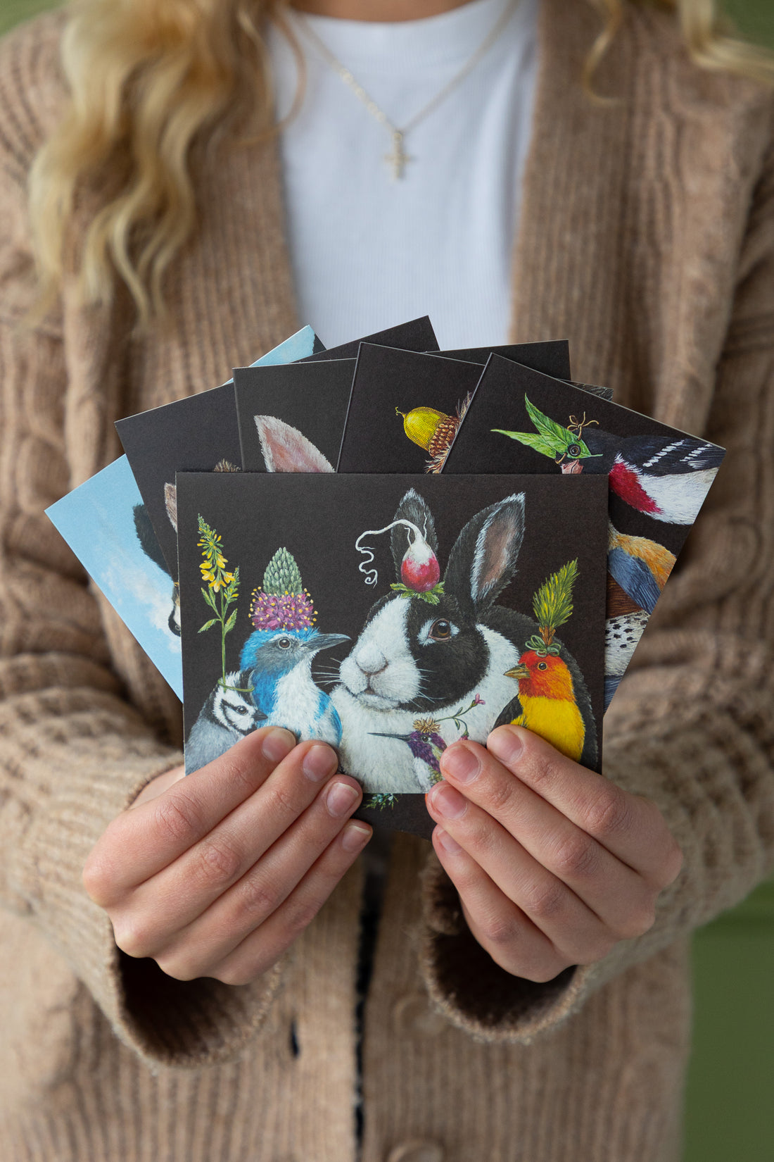 Person holding a collection of small artworks featuring animals.