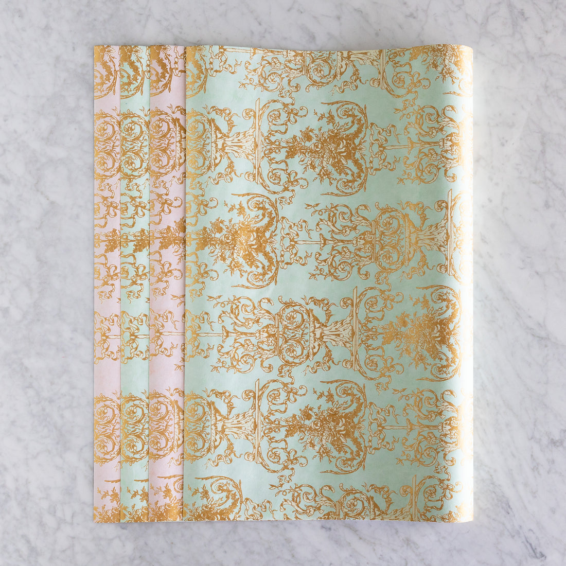 Decorative gift wrap paper in seafoam and pink with gold printing. 