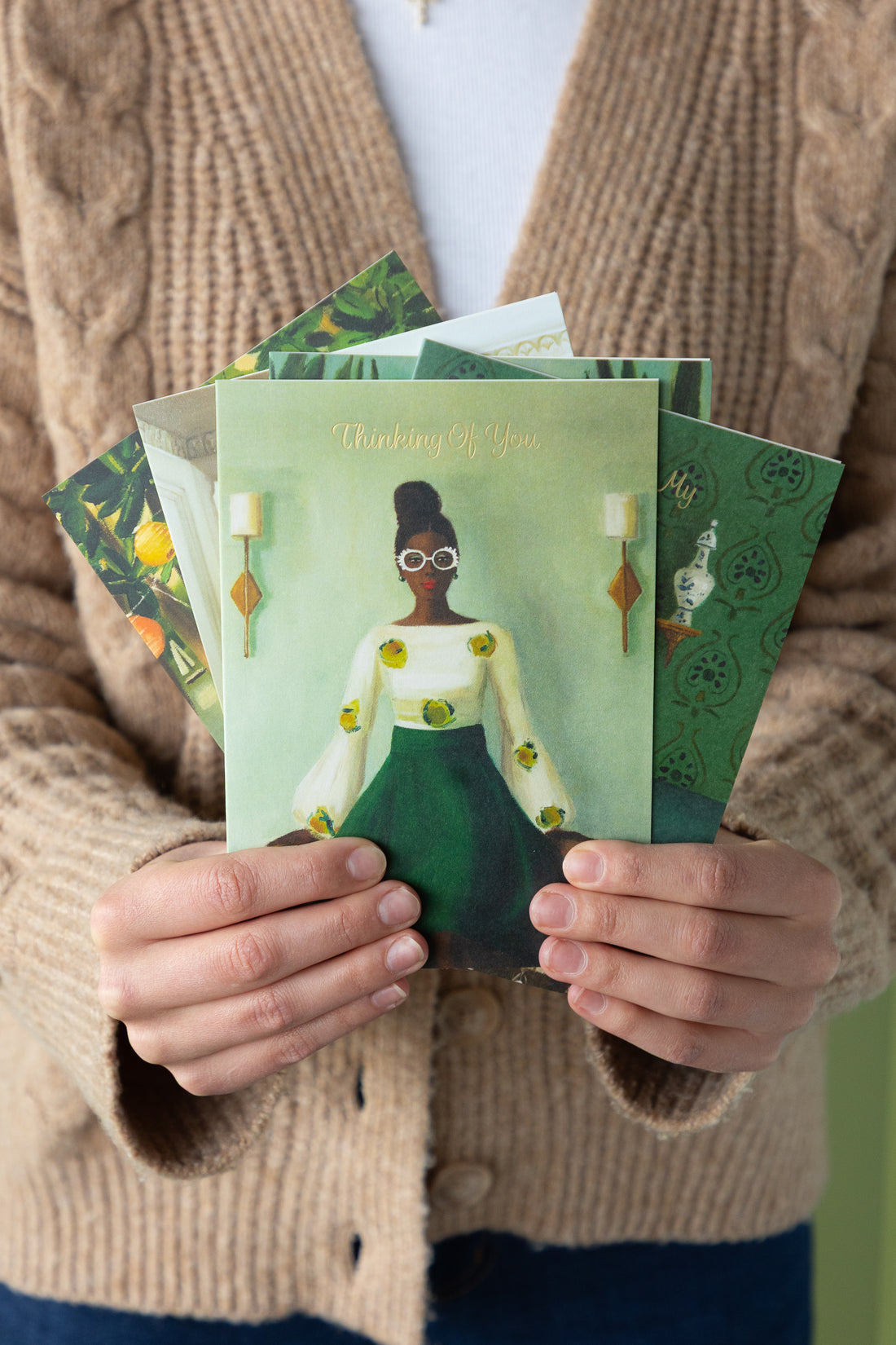 Person holding a stack of greeting cards with artistic designs.
