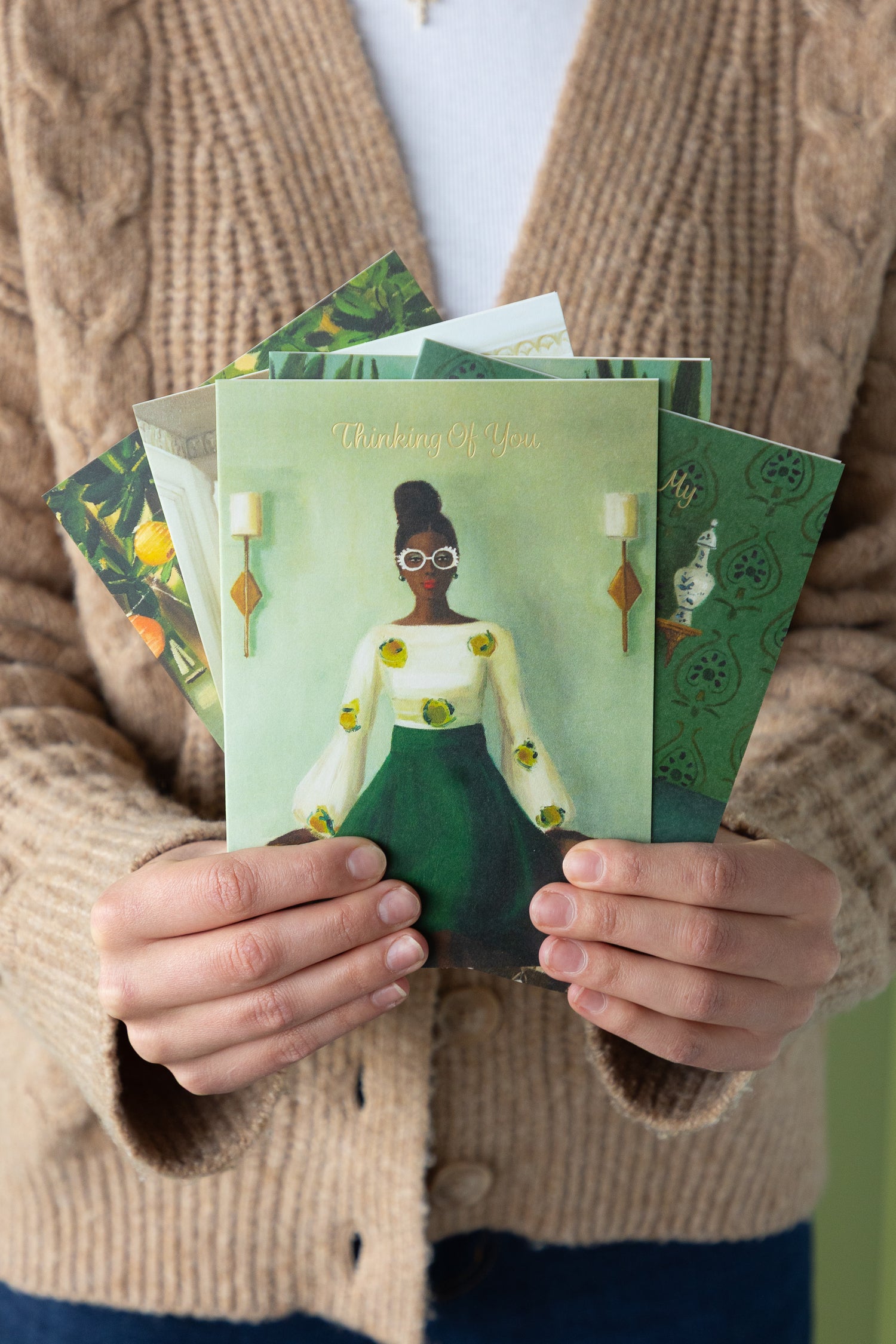 Person holding a stack of greeting cards with artistic designs.