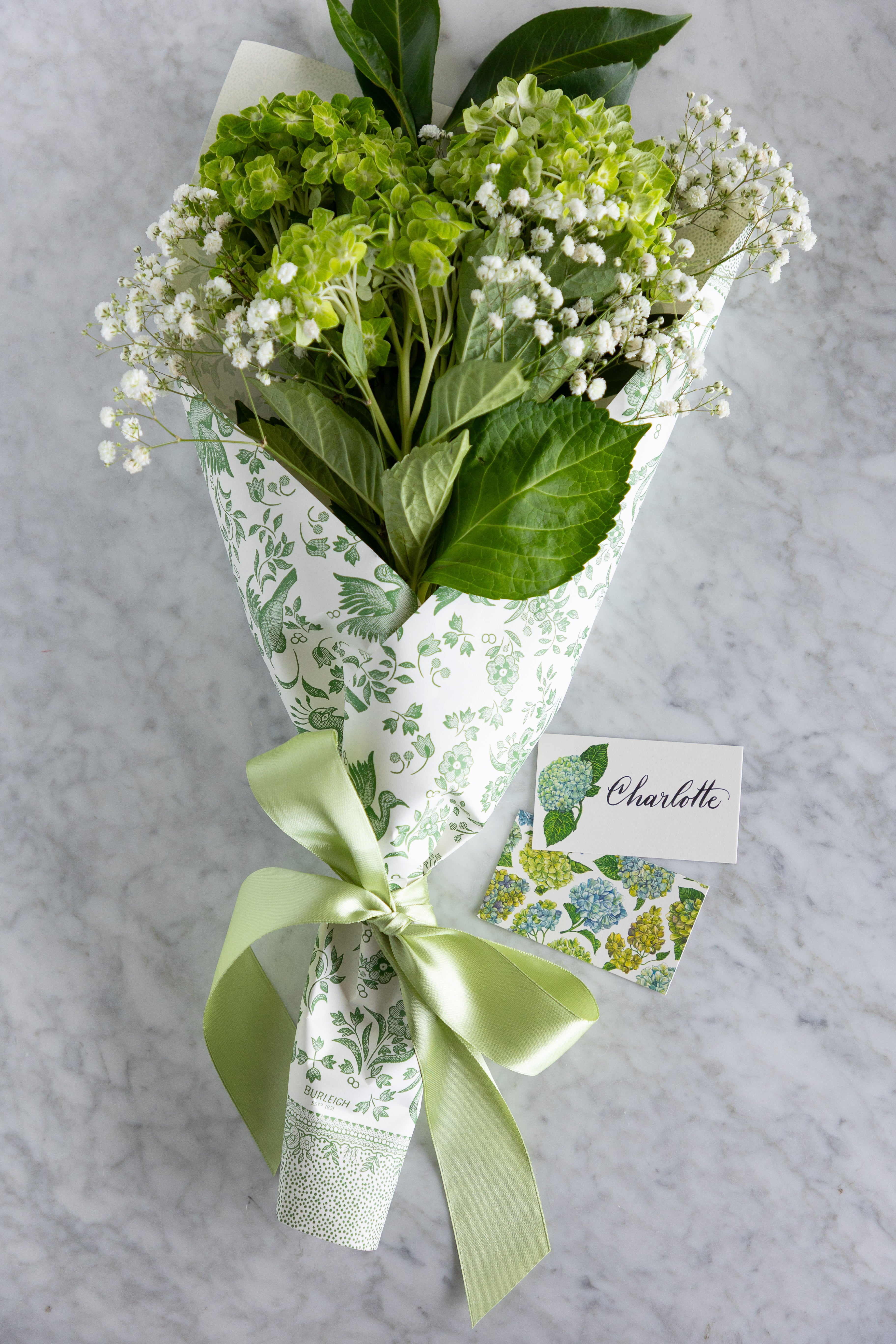 A bouquet of hydrangea tied with a ribbon with 2 tiny notes next to in. 