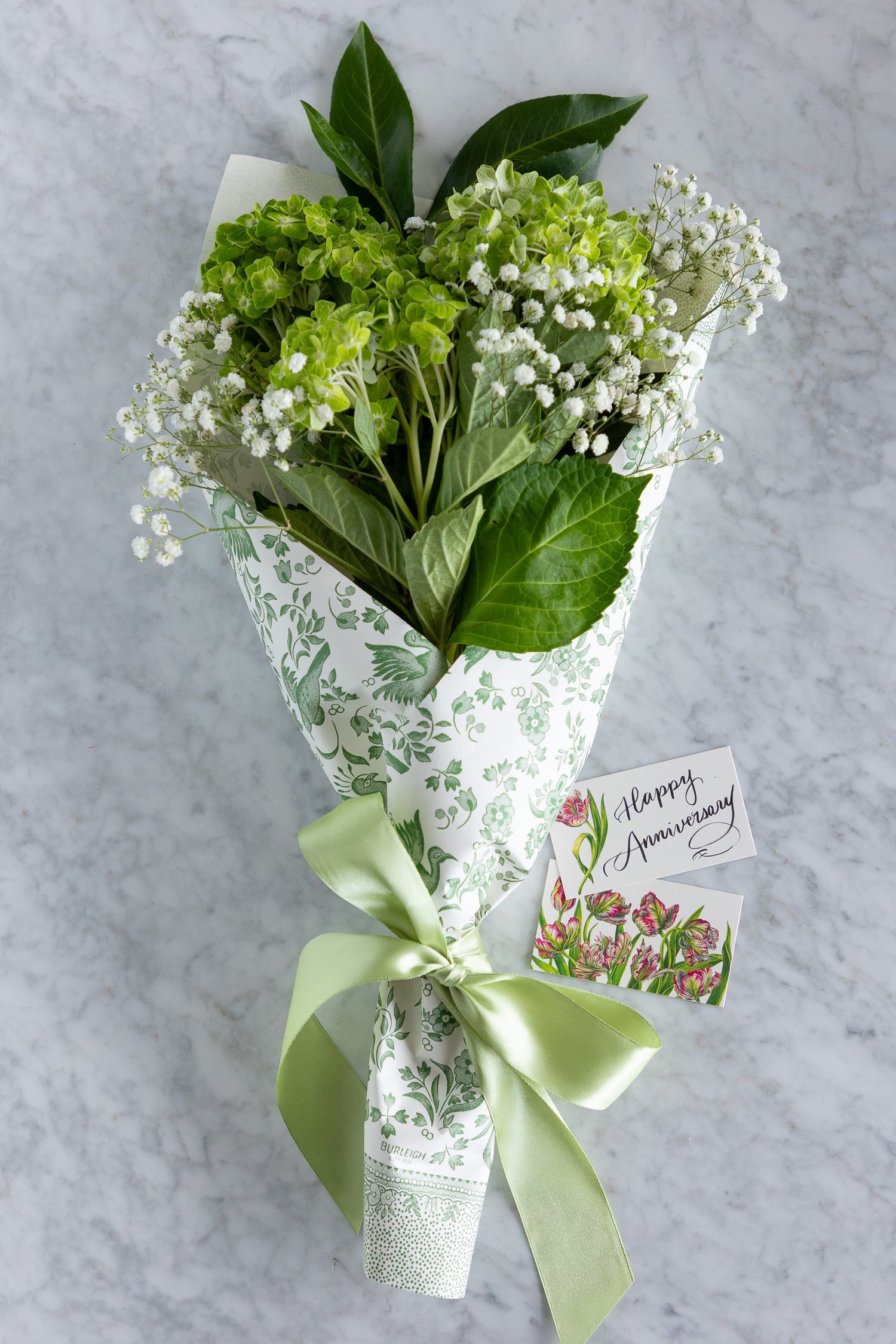 A wrapped bouquet of green hydrangeas and white baby&