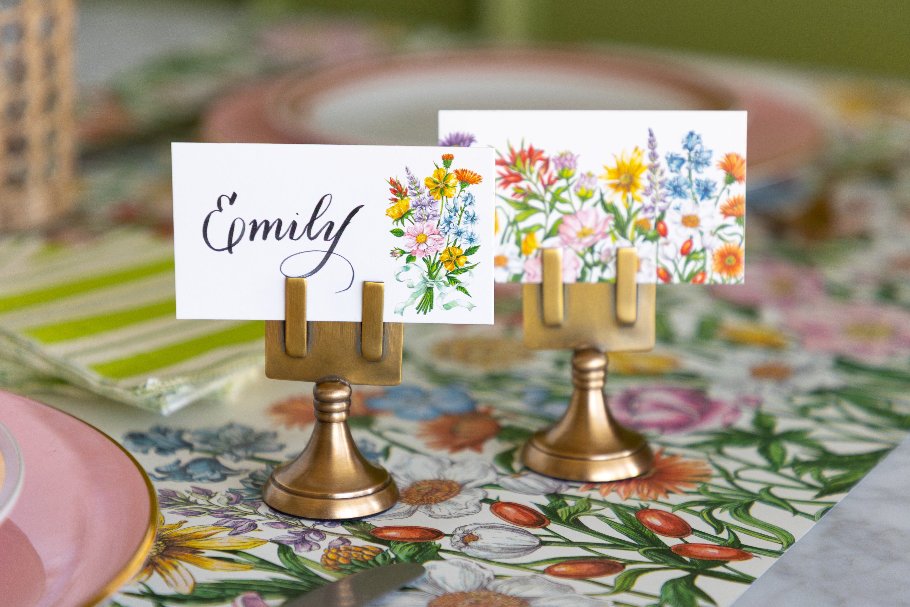 Two brass table place cards on stands, one printed with the name &