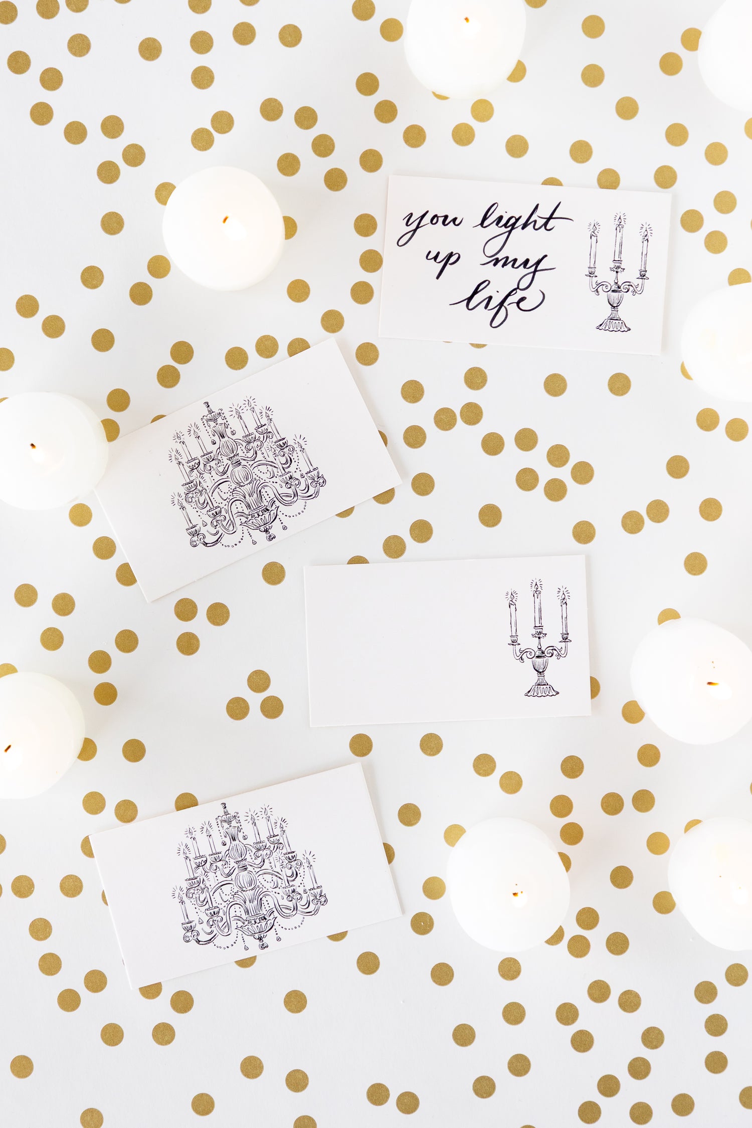 Three white rectangular cards with black line-art illustrations of chandeliers and one card with the phrase &