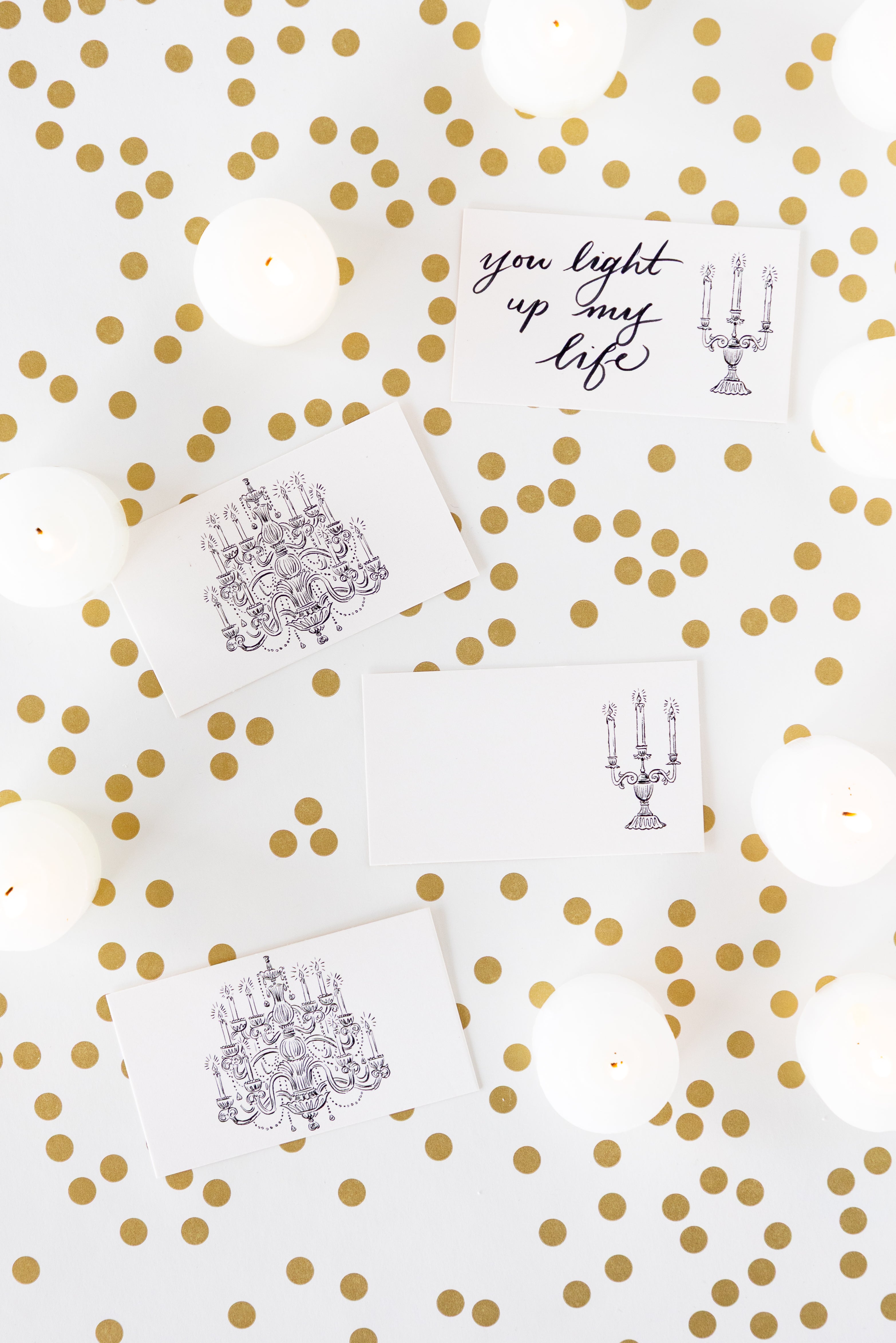 Three white rectangular cards with black line-art illustrations of chandeliers and one card with the phrase &