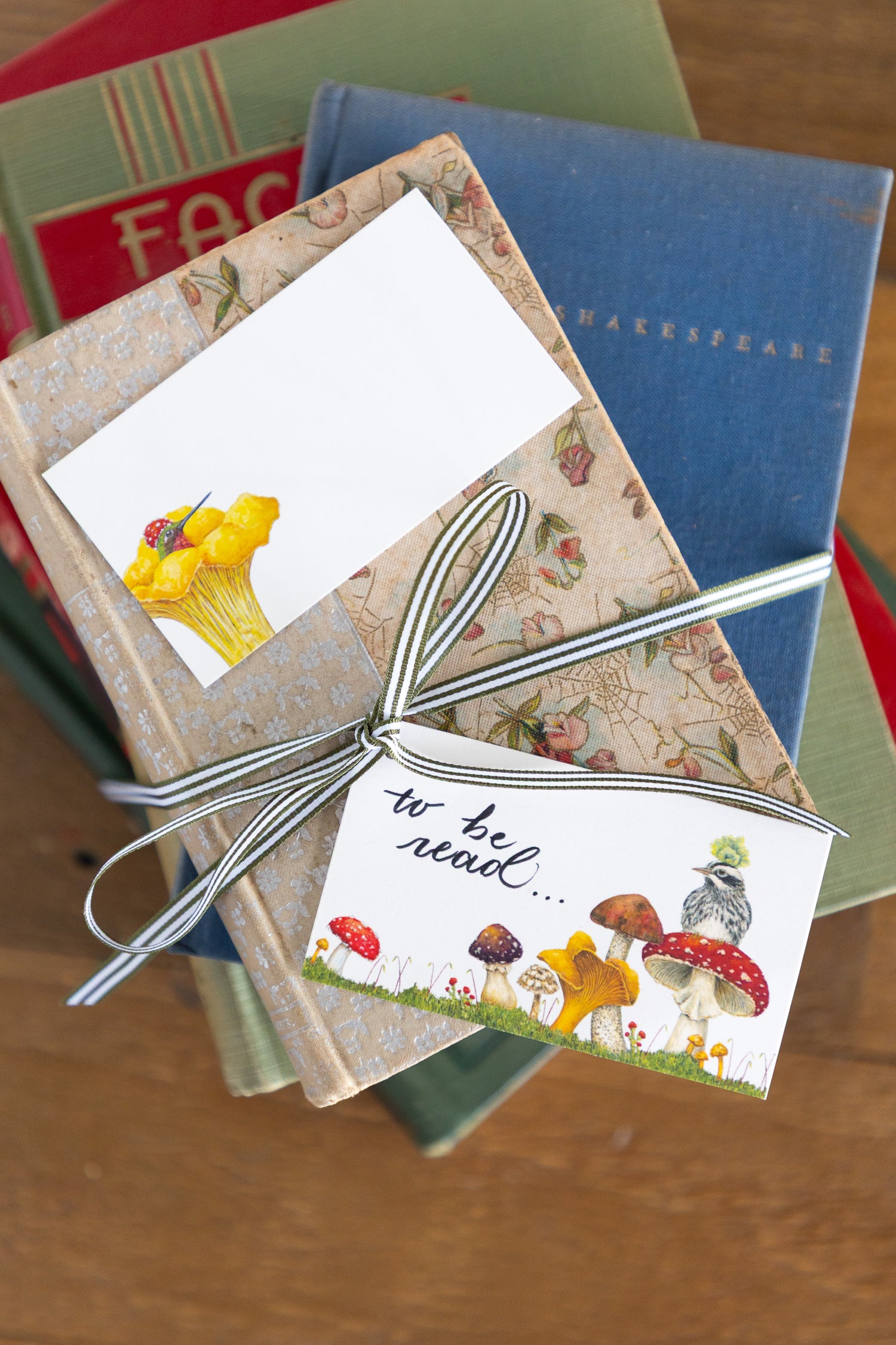 A stack of books with 2 tiny notes set on top of them.  One with the message &