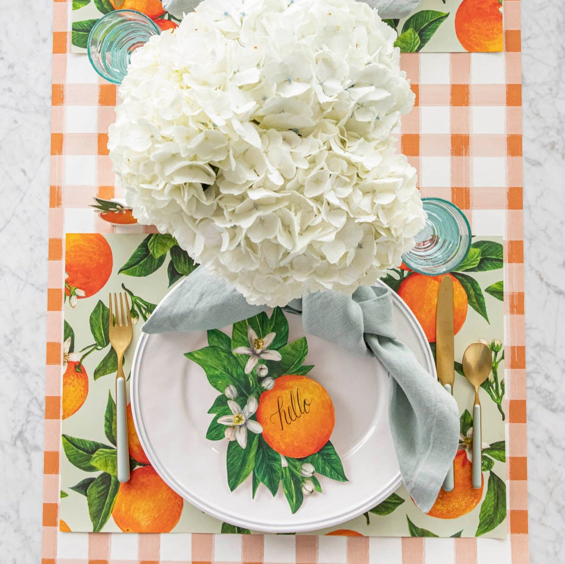 An elegant, citrus themed table setting featuring the Orange Painted Check Runner paired with Orange Orchard Placemat and Orange Table Accent.