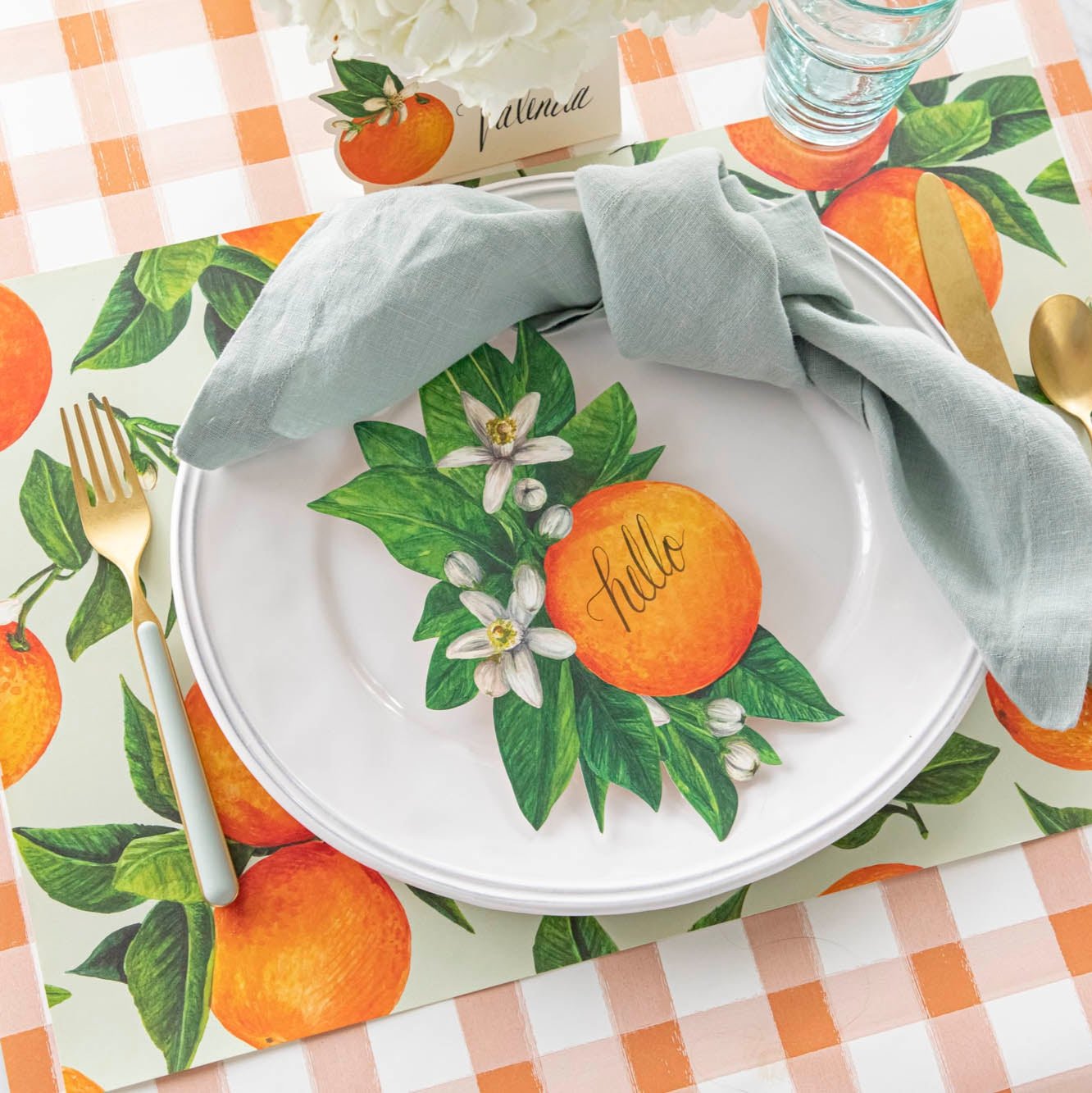 An elegant table setting featuring the Orange Blossom Table Accent with &quot;hello&quot; written on it and coordinating Orange Orchard Placemat and Orange Table Accent.