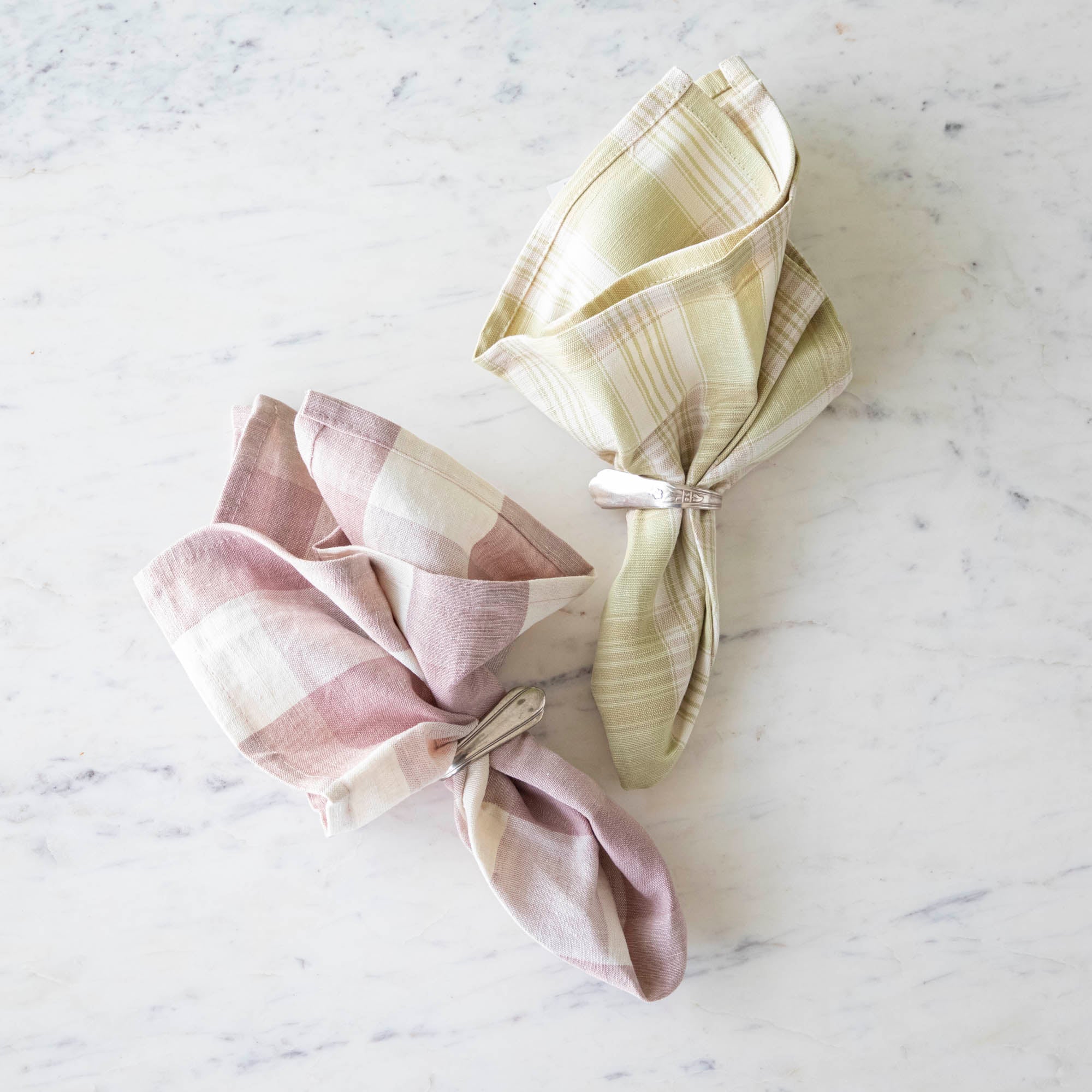 Vintage Rose Buffalo Check Cloth Napkin and Grapefruit Plaid Napkin in vintage silver napkin rings, on a marble table.