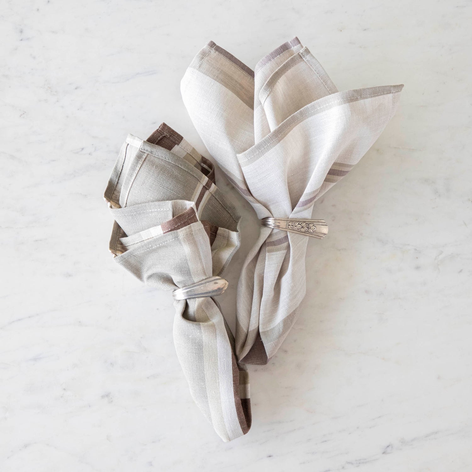 Dusty Pastel Striped Cloth Napkin and Oak Stone Cloth Napkin in vintage silver napkin rings on a marble table.