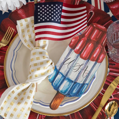 A patriotic place setting featuring a Rocket Pop Table Accent with &quot;USA&quot; written on it resting on the plate.