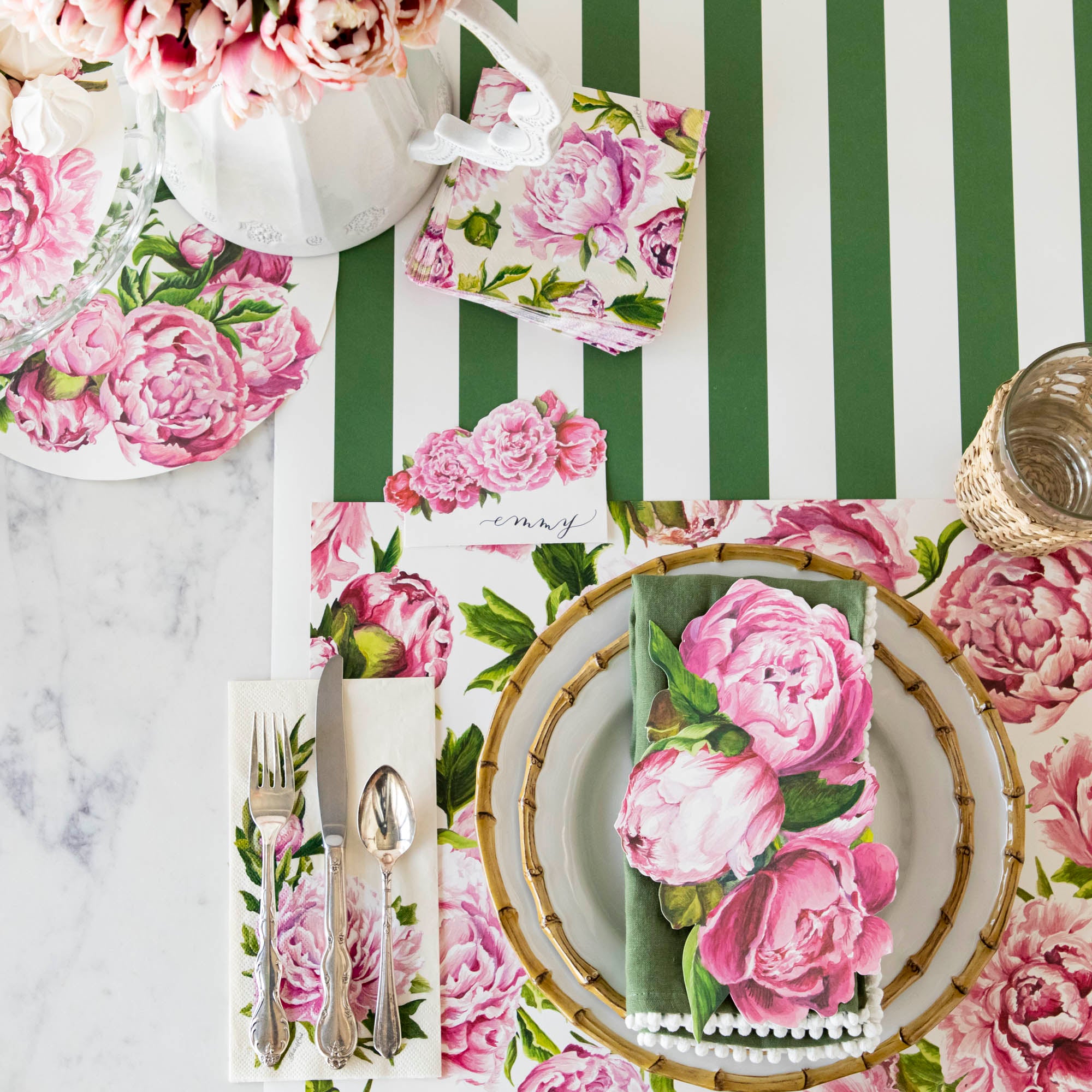 An elegant tablescape featuring Peonies In Bloom Placemats arranged on a green and white striped tablecloth by Hester &amp; Cook.