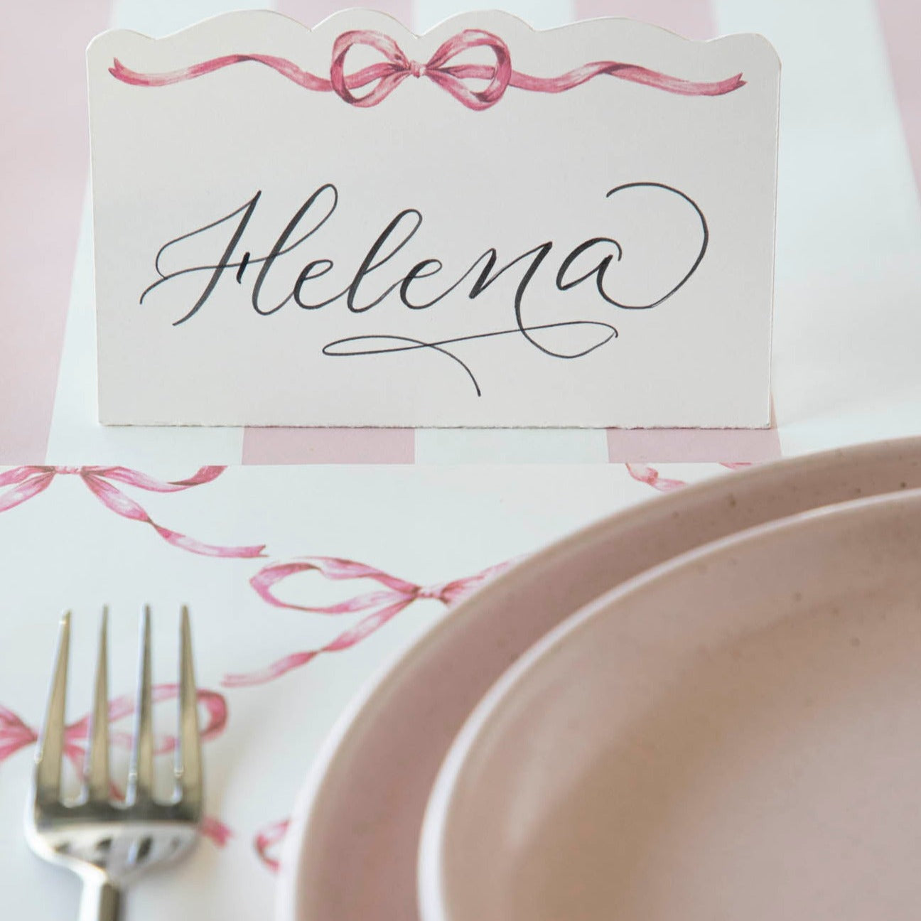 A Hester &amp; Cook Pink Bow Place Card is placed on a table, adding loveliness to the setting.