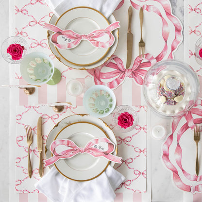 A Pink Bow Lattice Placemat by Hester &amp; Cook separates the plates and cutlery on the table.