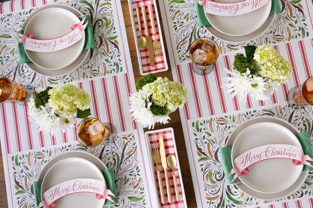 Christmas-themed table setting with plates, placemats, and centerpieces.